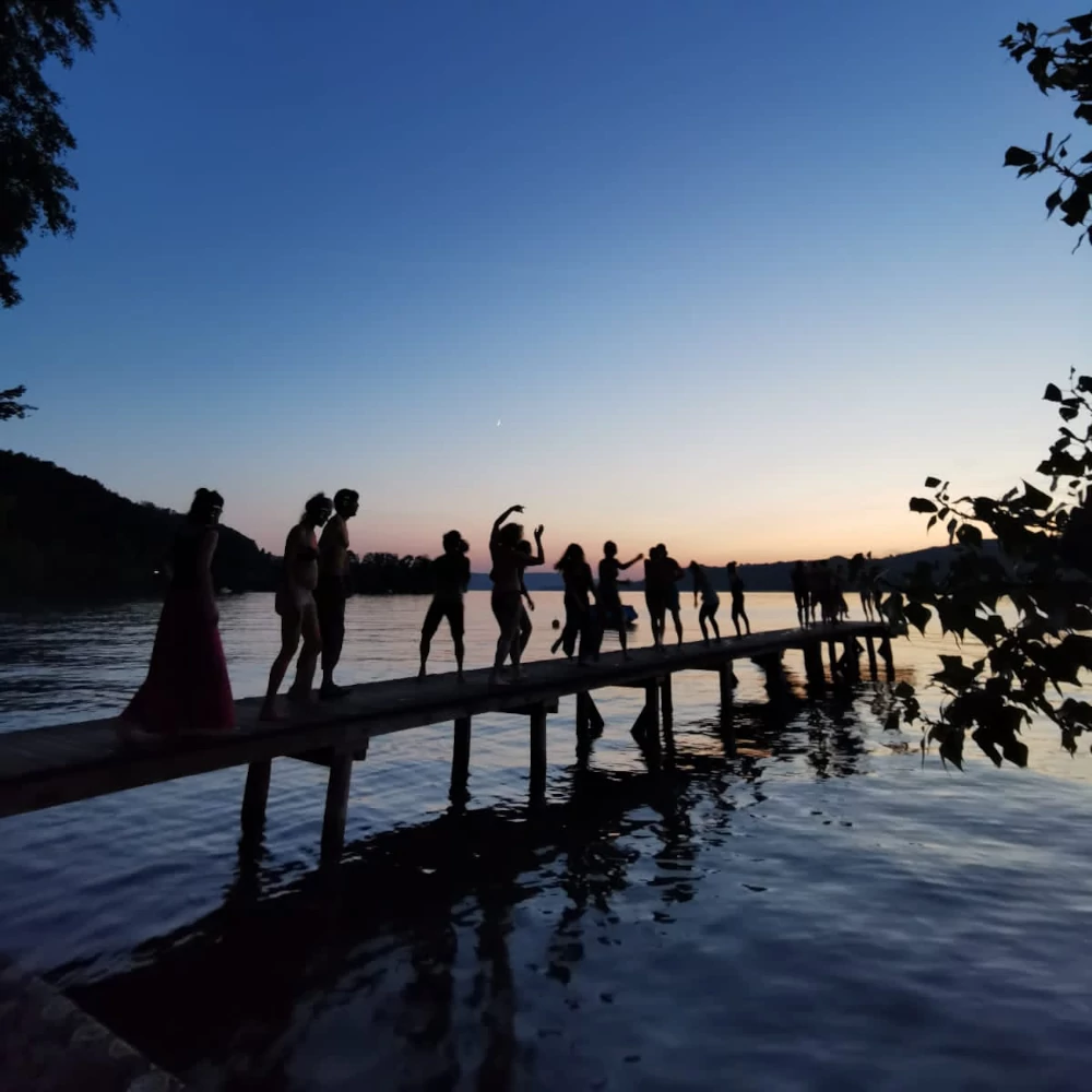 Tanzende auf Steg vor Dämmerungshimmel am Untersee